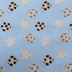 Könnte beinhalten: Ein hellblauer Stoff mit einem sich wiederholenden Muster aus braunen und beigefarbenen Punkten. Die Punkte sind unterschiedlich groß und haben eine leicht strukturierte Optik.