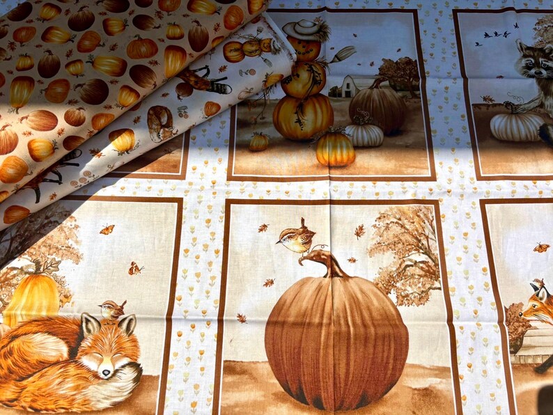 K&ouml;nnte beinhalten: Stoff mit Herbstthema, mit K&uuml;rbissen, Vogelscheuchen und Waldtieren. Der Stoff hat ein sich wiederholendes Muster aus K&uuml;rbissen in Orange- und Braunt&ouml;nen. Zus&auml;tzliche Paneele zeigen Szenen mit F&uuml;chsen, V&ouml;geln und K&uuml;rbissen. Der Stoff ist gefaltet.