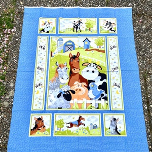 Può includere: Un pannello di tessuto blu con un tema di animali della fattoria. L'immagine centrale mostra un cavallo, una mucca, una pecora, un maiale e un uccello. Pannelli più piccoli raffigurano mucche, cavalli e scene di fattoria. Il bordo ha un motivo blu con piccole forme bianche.