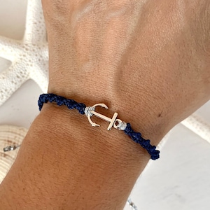 Könnte beinhalten: Ein geflochtenes Armband in Marineblau mit einem silbernen Anker-Anhänger.