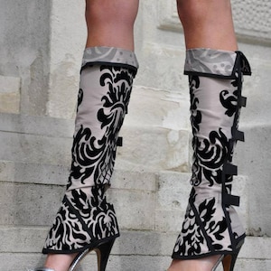 May include: A pair of black and white patterned leg warmers with a black trim and a high heel. The leg warmers are made of a soft, stretchy fabric and have a comfortable fit.