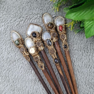 May include: Seven wooden hair sticks with carved details and gemstone accents. Each stick features a different gemstone, including a green stone, a black stone, a red stone, and a clear stone.