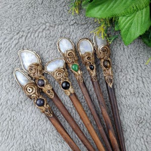 May include: Seven wooden hair sticks with moonstone tops and various colored gemstone accents. The sticks are brown and have intricate carvings.
