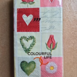 Könnte beinhalten: Eine Packung dekorativer Papierservietten mit einem sich wiederholenden Muster aus Herzen, Rosen und Gänseblümchen. Die Servietten sind in verschiedenen Farben gehalten, darunter Rot, Rosa, Grün und Gelb. Der Text "COLOURFUL LIFE" ist auf die Servietten gedruckt.