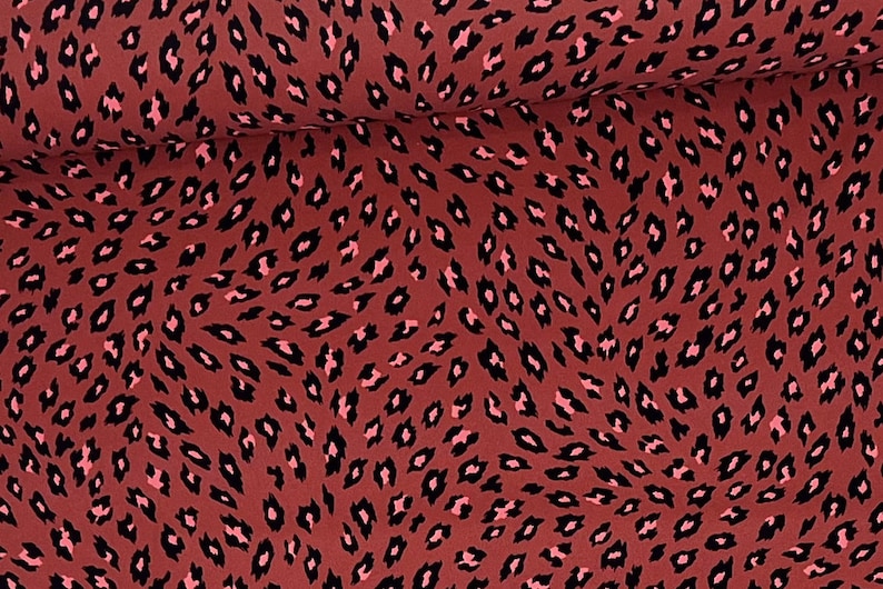May include: Red fabric with a black and pink leopard print pattern.