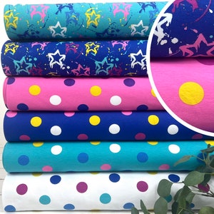 May include: Stack of six fabric rolls with different polka dot patterns. The rolls are in various colors, including pink, blue, turquoise, and white. The polka dots are yellow, white, and pink.