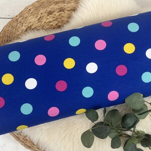 May include: Blue fabric with a polka dot pattern. The dots are in various colors, including pink, yellow, white, and turquoise.