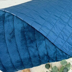 May include: A teal blue quilted fabric with a soft, plush texture on the reverse side. The fabric is folded in half, showing both sides.