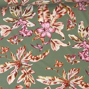 May include: Green fabric with a floral pattern featuring pink flowers and white and red leaves.