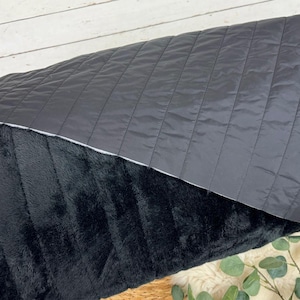 May include: A black and gray reversible throw blanket. One side is a soft, plush faux fur and the other side is a quilted fabric.