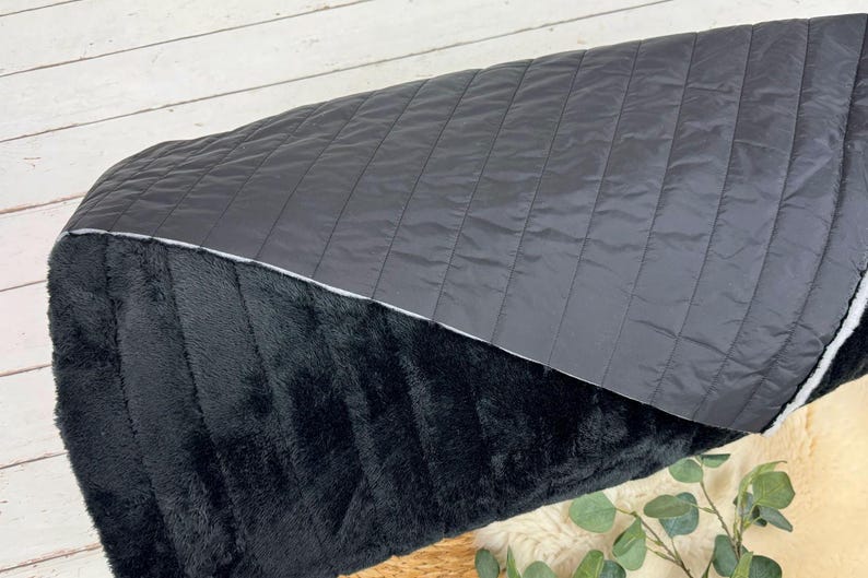 May include: A black and gray reversible throw blanket. One side is a soft, plush faux fur and the other side is a quilted fabric.