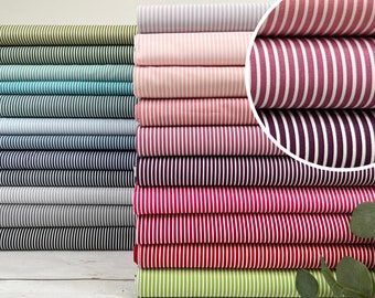 May include: A collection of striped fabric stacks in shades of green, blue, pink, and red. Each stack features a different colour combination with vertical white stripes. The fabrics are likely cotton or a similar material, ideal for sewing and crafting.