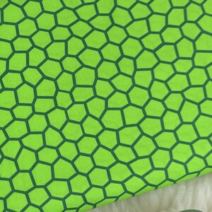 Könnte beinhalten: Hellgrüner Stoff mit einem dunkelgrünen Wabenmuster. Das geometrische Design besteht aus unregelmäßigen Sechsecken und erzeugt eine strukturierte Optik. Geeignet für Näh- oder Bastelprojekte.