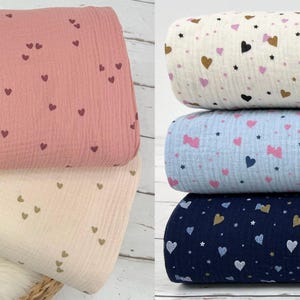 Könnte beinhalten: Vier verschiedene Stoffmuster mit verschiedenen Herz- und Sternmustern. Die Stoffe sind in Rosa, Creme, Hellblau und Dunkelblau.