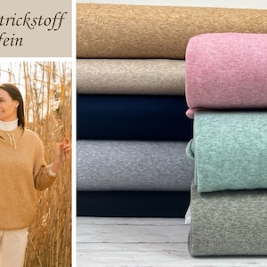 Könnte beinhalten: Ein Stapel weicher Strickstoffrollen in verschiedenen Farben, darunter Beige, Rosa, Grün, Grau und Blau. Der Stoff ist ein feines Strickgewebe, perfekt für Nähprojekte. Der Text "Soft Strickstoff fein" ist im Bild sichtbar.
