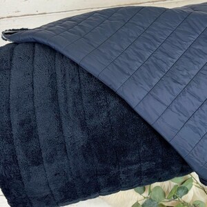 May include: A black and blue reversible pet bed. One side is made of a soft, plush fabric and the other side is a quilted fabric.