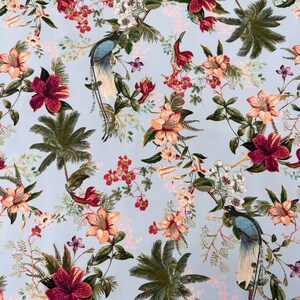 May include: A light blue fabric with a tropical print featuring pink, red, and green flowers, palm trees, and peacocks.