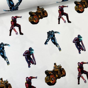Può includere: Un tessuto bianco con un motivo ripetuto di figure futuristiche in rosso, blu e grigio che cavalcano motociclette futuristiche. Le motociclette sono dorate e nere con ruote arancioni luminose.