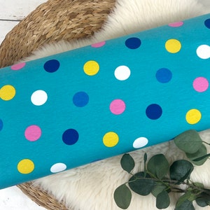May include: A turquoise blue fabric with a polka dot pattern. The dots are in various colors, including yellow, white, pink, and blue.