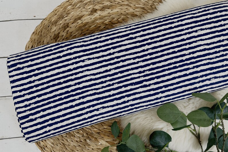 Pu&ograve; includere: Un tessuto bianco con strisce orizzontali blu navy. Le strisce hanno un effetto pennellato e usurato.