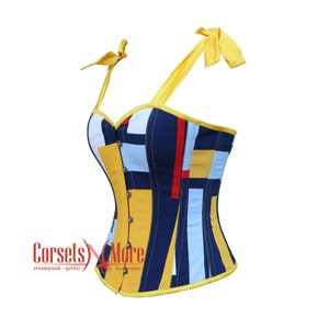May include: A yellow, blue, red, and white patterned corset with a single yellow strap and bow. The corset has a busk closure in the front and is made of a sturdy fabric.