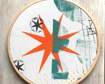 Star in orange - round screen-printed picture in an embroidery frame