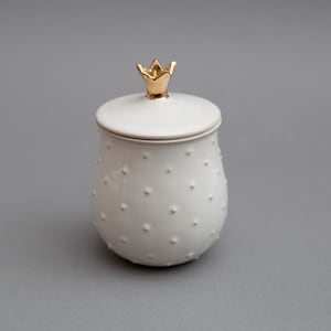 May include: White ceramic jar with a gold crown lid. The jar has a textured surface with small white dots.