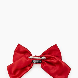 May include: A large red satin bow with a silver clip. The bow has a black tag with the text "My Swag" on it.