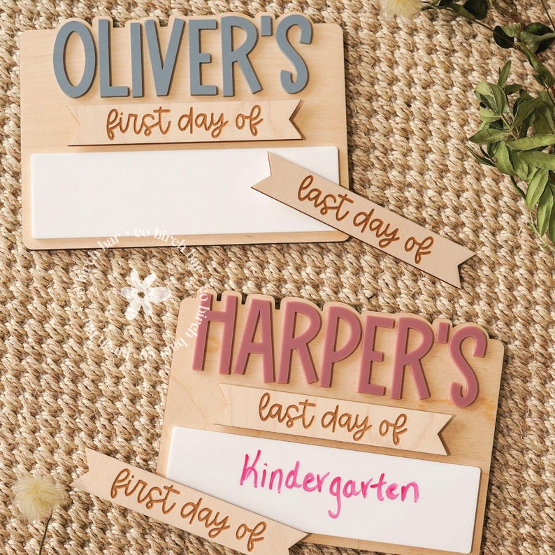 May include: Wooden school sign with the name "Oliver's" in gray letters and "first day of" in brown. Below is a white space for writing. A separate banner says "last day of". Another sign says "Harper's" and "Kindergarten".