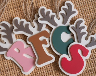 May include: Five wooden ornaments shaped like reindeer antlers with the letters R, F, C, S painted in pink, brown, green, and red.