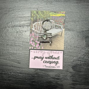 May include: A silver keychain with a heart-shaped charm and a bench design. The keychain has a pink card attached with the text "...pray without ceasing. 1 Thessalonians 5:17"