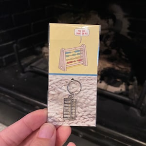 May include: A silver abacus keychain with a yellow card that says "You can count on me!" with a cartoon abacus on it.