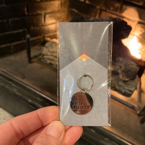 May include: A silver keychain with a round tag that says "Be the Light".