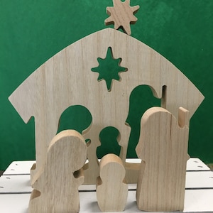 May include: Wooden nativity scene with a star on top of the stable. The figures are of Mary, Joseph, and baby Jesus. The figures are all made of unfinished wood.