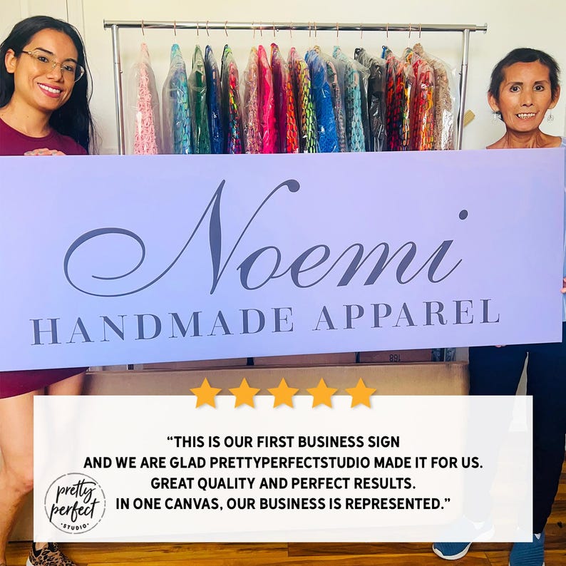 Shop owner holding personalized indoor business sign used for company branding.