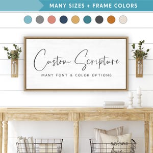 May include: A framed wooden sign with the words "Custom Scripture" in elegant script. The sign is white with black text and a light brown frame. The text "MANY FONT & COLOR OPTIONS" is below the main text. The top of the image shows color options.