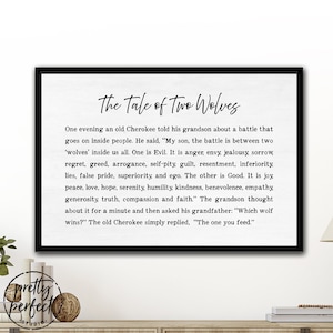 May include: A rectangular wall art piece in a black frame featuring the text The Tale of Two Wolves. The white background displays the full Cherokee parable about two wolves representing good and evil, printed in a clear black serif font.