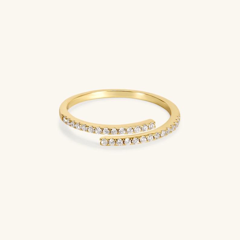 May include: A gold ring with a delicate design featuring two rows of small diamonds set in a continuous line.
