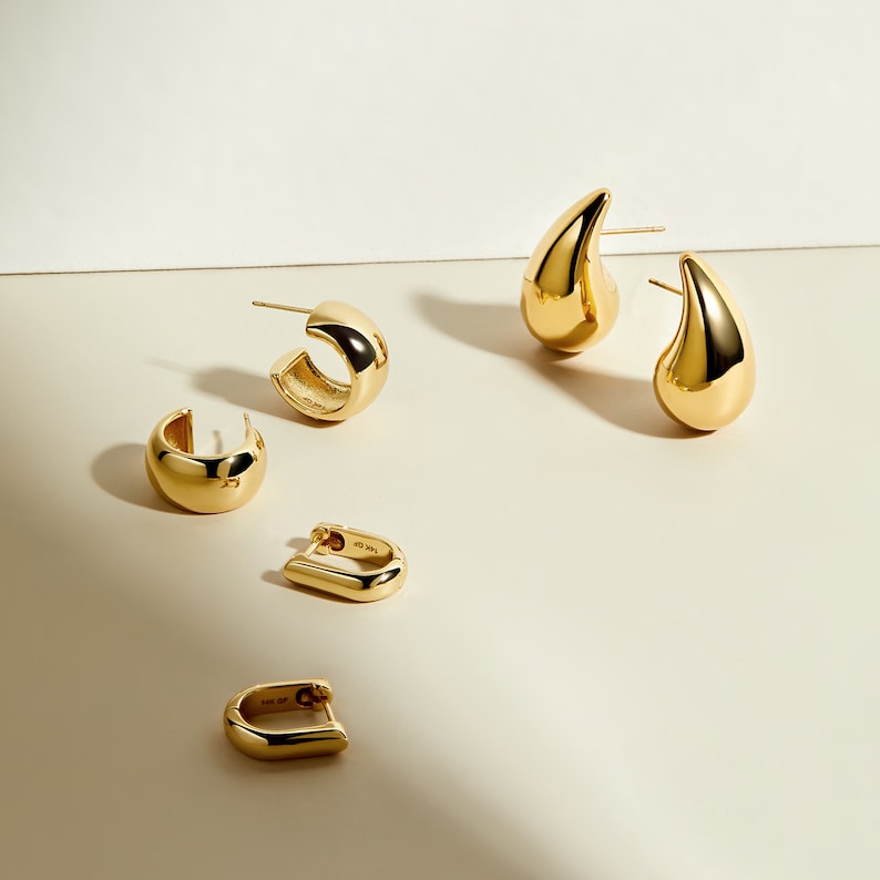 May include: Four gold earrings, two are hoop style and two are teardrop shaped.