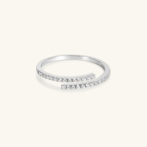 May include: A silver ring with a delicate design featuring two bands of small diamonds that intersect.