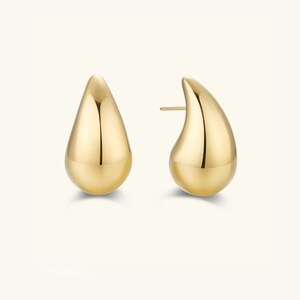 May include: A pair of gold teardrop-shaped earrings. The earrings are smooth and shiny.