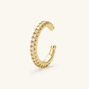 May include: A gold ear cuff with a row of clear cubic zirconia stones.