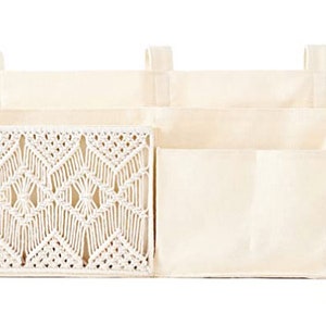 May include: A white canvas hanging organizer with three pockets. The top pocket has a woven macrame design.