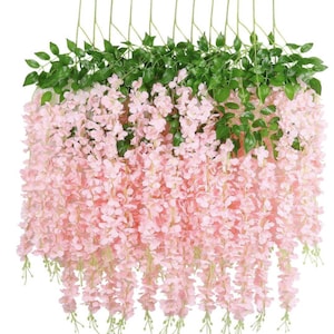May include: A set of 10 artificial wisteria flower garlands with pink flowers and green leaves. The garlands are hanging down and are perfect for adding a touch of spring to your home decor.