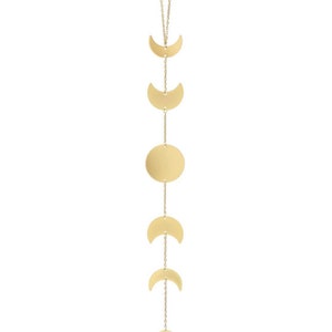 May include: A gold-colored metal wall hanging featuring the phases of the moon. The design includes crescent moons and a full moon disc, all connected by delicate chains. The celestial-themed decor is ideal for adding a touch of cosmic elegance to any space.