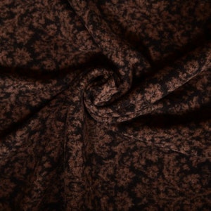 Könnte beinhalten: Nahaufnahme eines braunen Stoffes mit einem schwarzen Blumenmuster. Der Stoff ist weich und texturiert, mit einem dezenten Glanz.