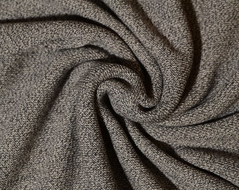 Op de afbeelding: Close-up van een grijze en witte textuurstof met een draaiende structuur.