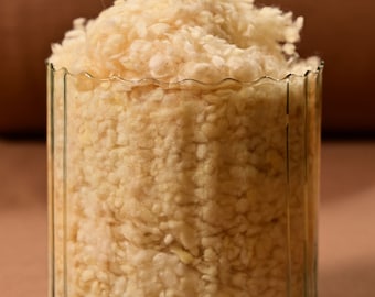 May include: A clear glass jar with a fluted rim filled with white fluffy material.