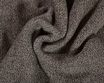 Op de afbeelding: Close-up van een donkergrijze, textuurrijke stof met een subtiel geweven patroon. De stof is zacht en heeft een licht pluche textuur.