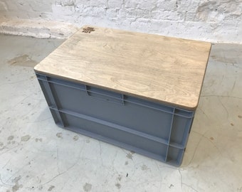 May include: A gray plastic storage bin with a wooden top. The top has the words "The Crate Cafe Box" printed on it.